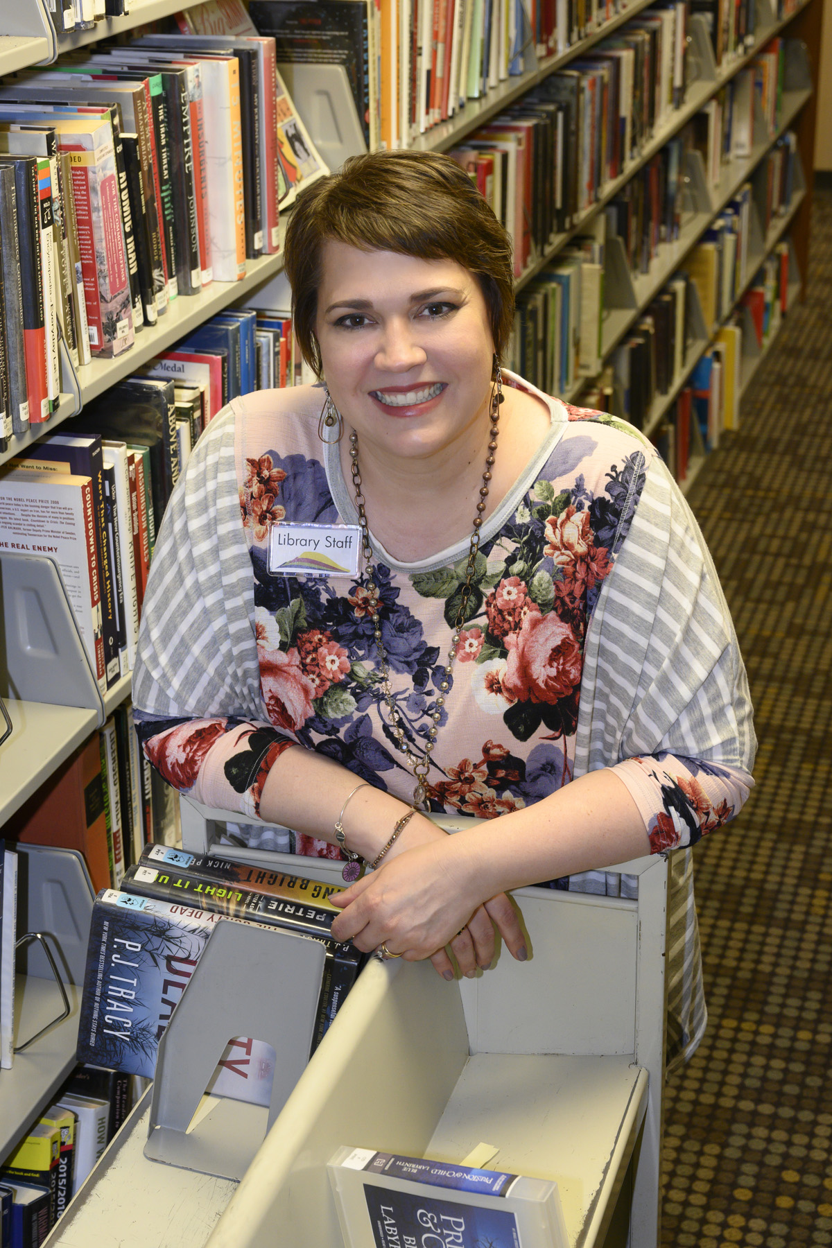 Lynn Engen with rolling book cart in the library.