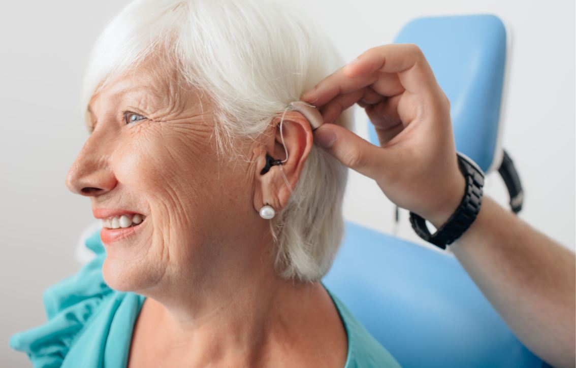 Clinician placing hearing aid on woman's ear
