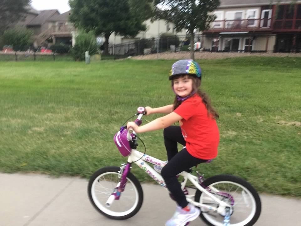 Amelia loves bike riding. One day, she will achieve her goal of riding without the training wheels!