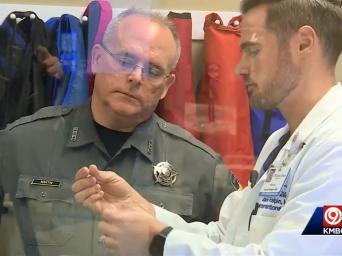 KMBC 9 abc. Dr. Jared Halpin showing thrombectomy device to Sheriff Martin