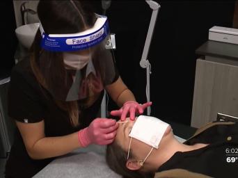 41 Action News. Estheician waxing woman's eyebrows wearing face shield and gloves.