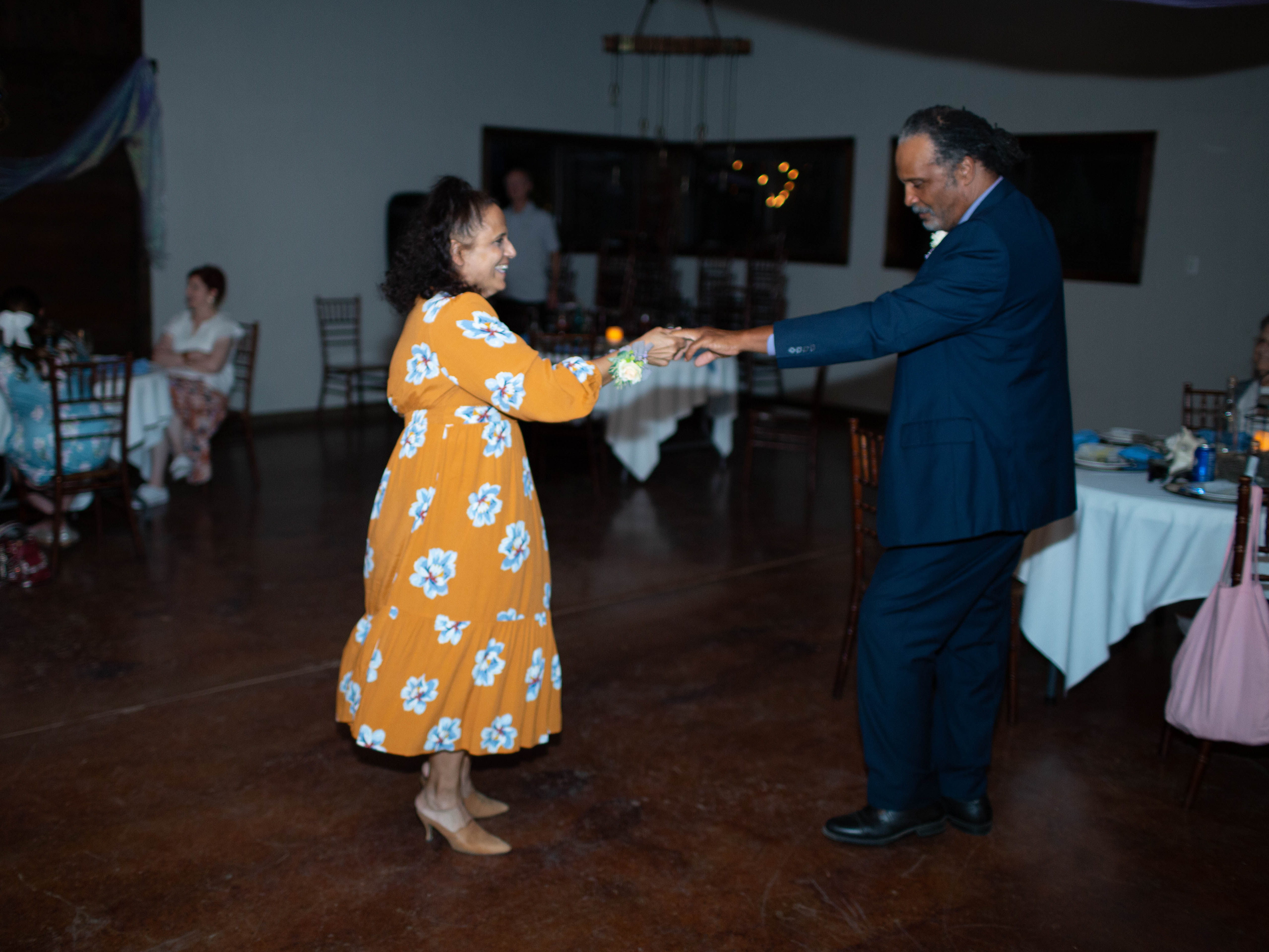 A women in an orange dress dancing with a man in a blue suit
