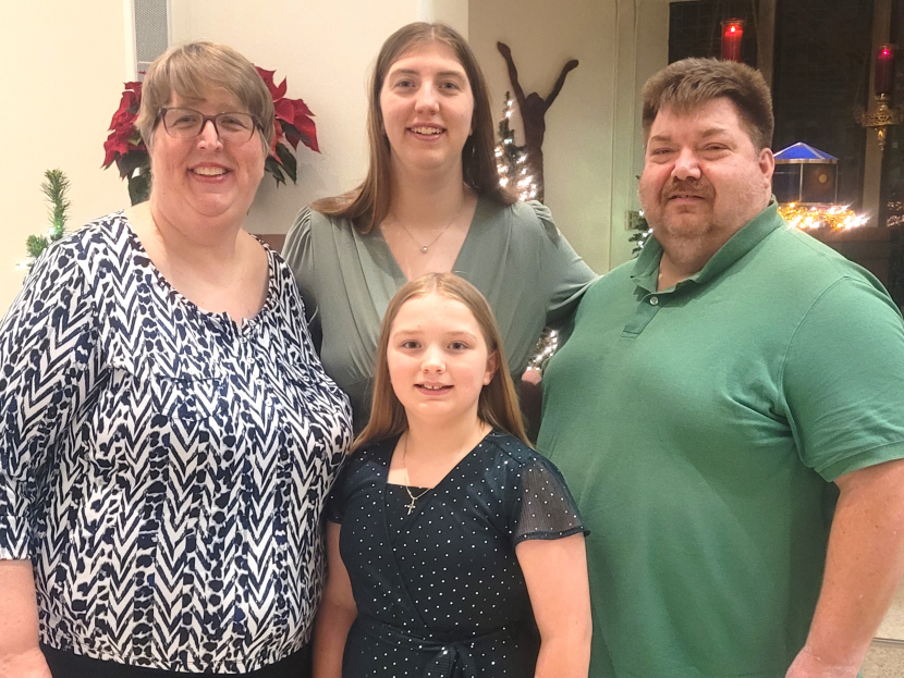 A smiling family of four, looking at the camera