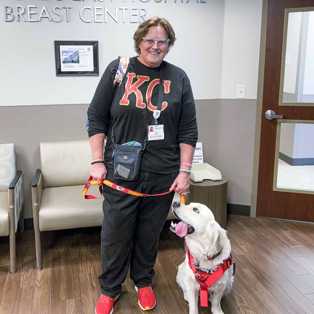 Nina Noe, a breast cancer patient, poses in the Saint Luke's East Breast Center with her therapy dog, a golden retreiver.