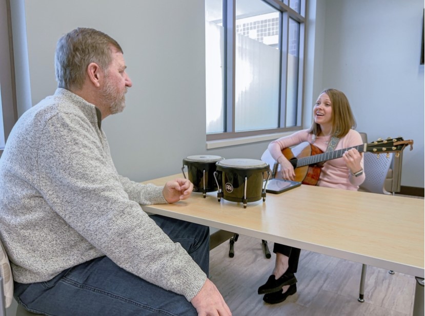 Kevin with his music therapist Amy work with drums and a guitar