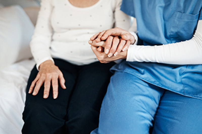 A caregiver is holding the hand of a patient