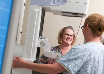 A nurse stands by a 3-D mammography machine