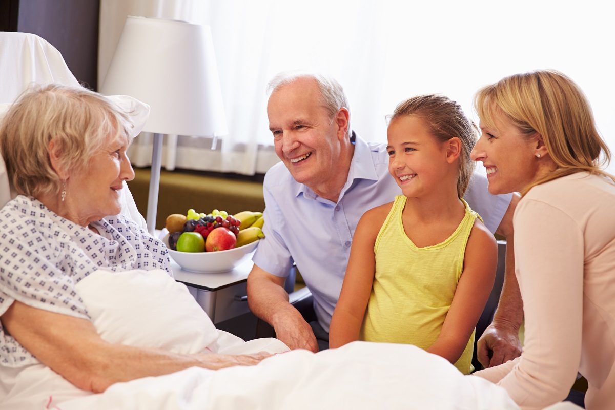 A family speaks with a patient in a skilled nursing facility