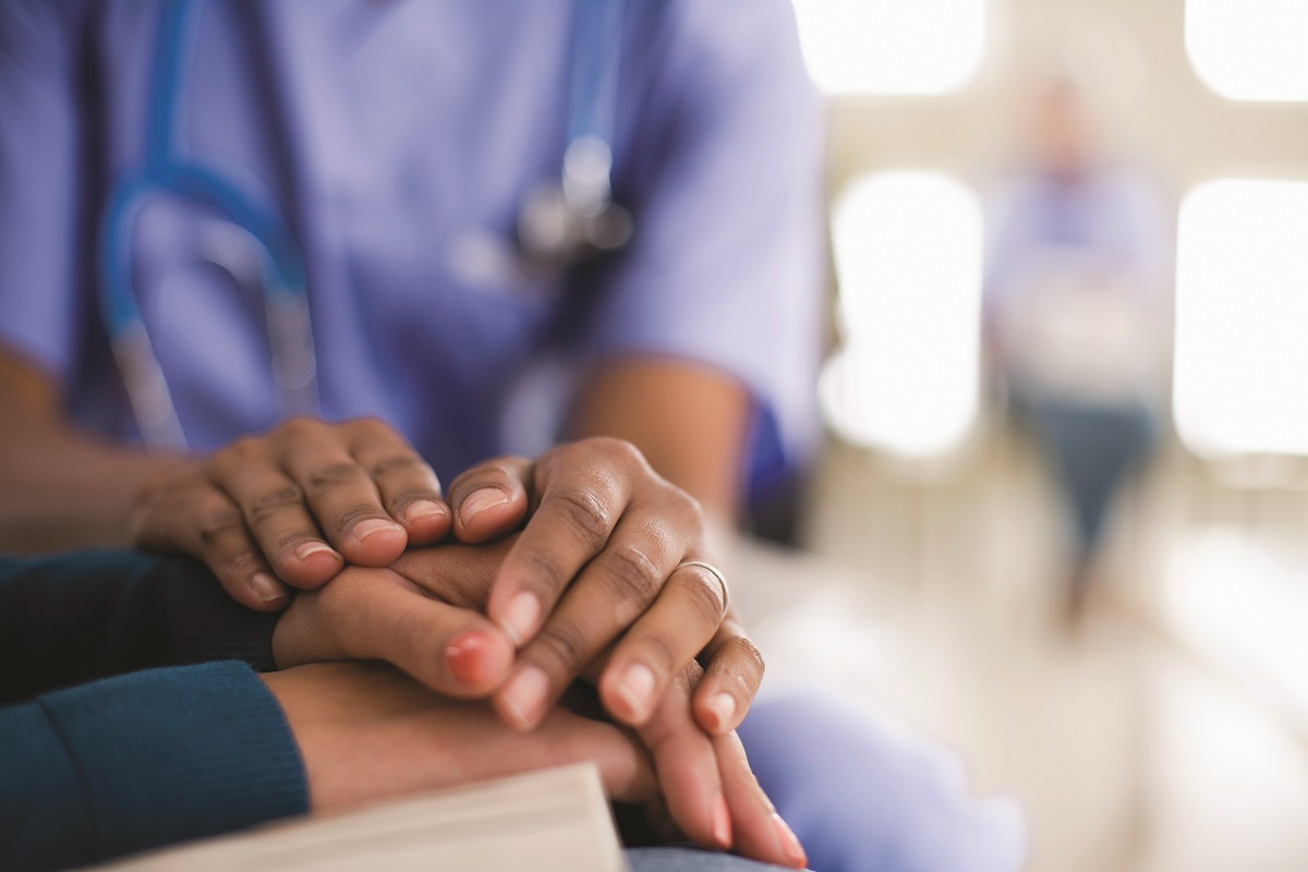 A caregiver holds a patient's hand