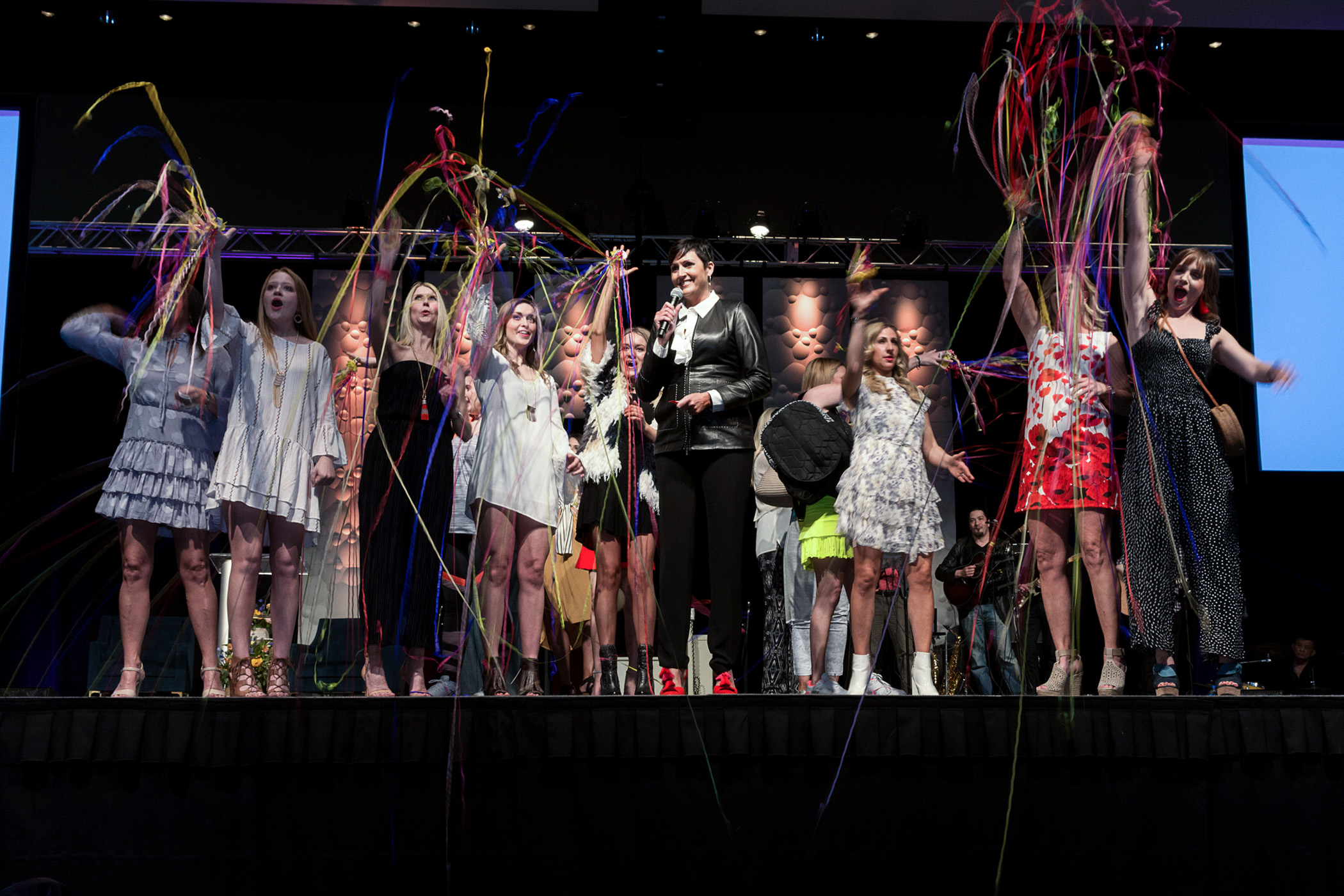 Guests on stage at Books and Boutiques celebrating by throwing streamers while raising funds for Saint Luke's Rehabilitation Institute