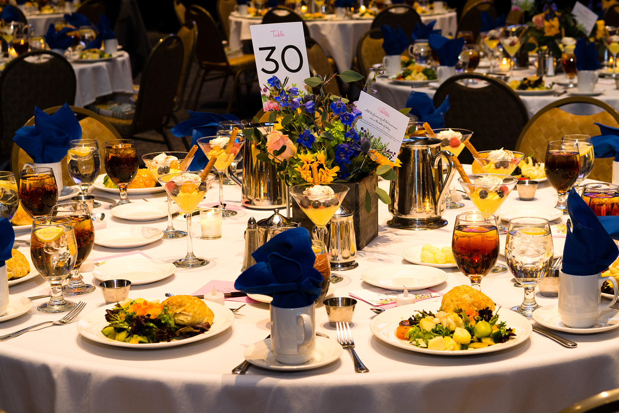 Tables with flowers and blue accents with food and drinks for the guests of the 2018 Books and Boutique 