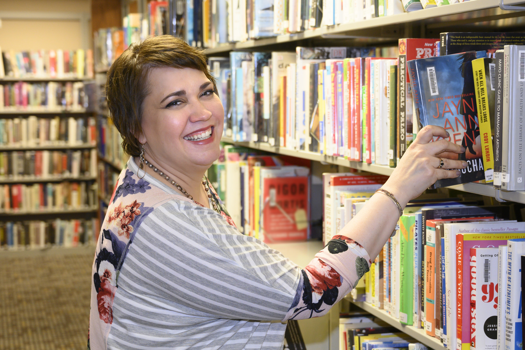 Lynn Engen getting a book off the shelf at the library.