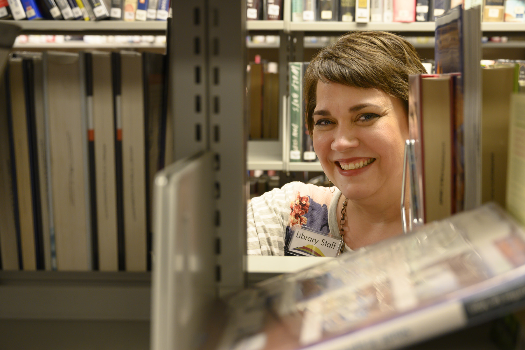 Lynn Engen smiling through a bookshelf.