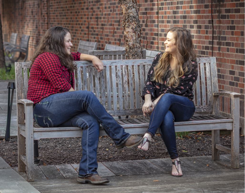 Brooke and Kayla Norman talking on a bench