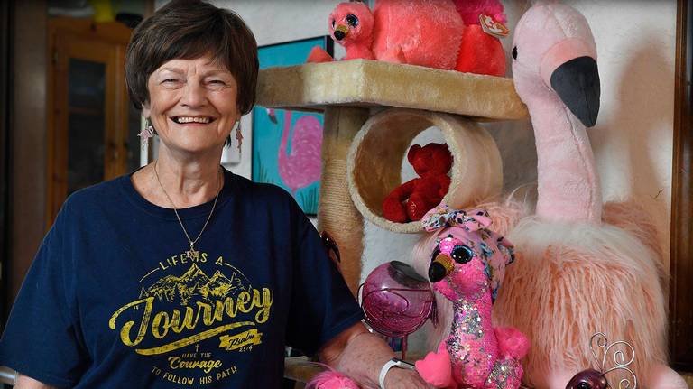Nita Jestila smiling with her flamingo collectibles in her home