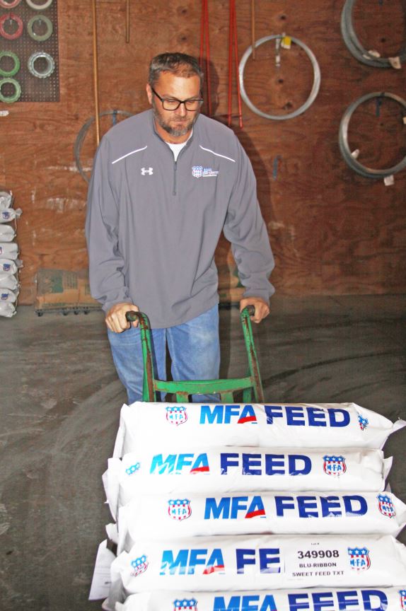 Dustin Cox moving bags of feed at work.