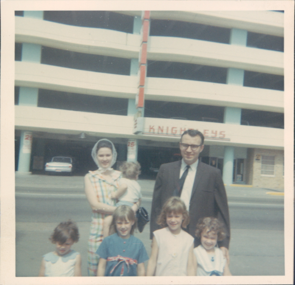 The Zollar family, with all five children in front of a building. 