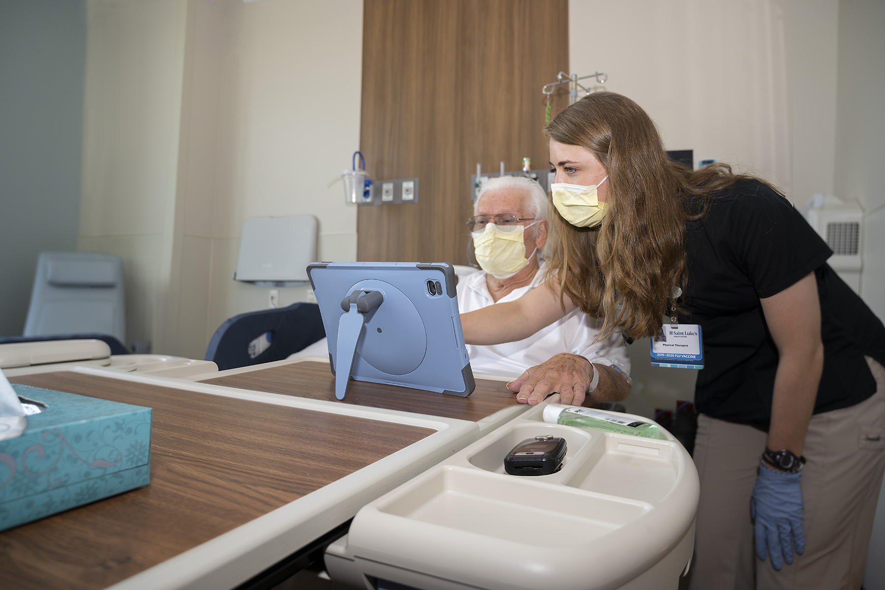 A Saint Luke's physical therapist helps connect Don and his daughter in a video chat through Saint Luke's Friends and Family Program. 