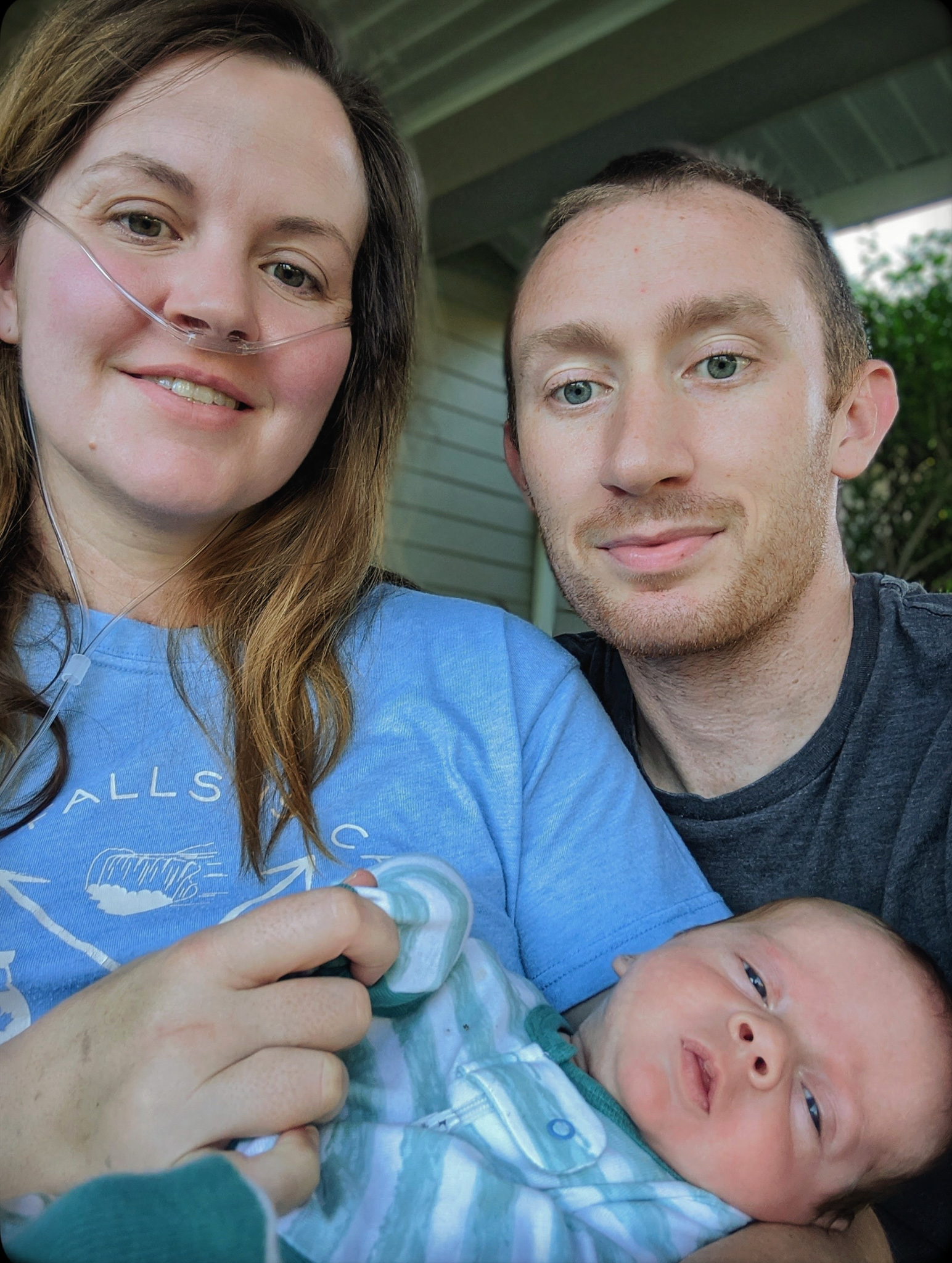 Laura and Andrew smiling, holding their newborn baby Logan