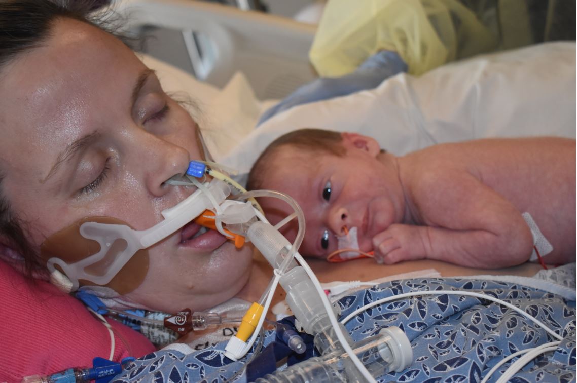 Laura Steeves hooked up to a ventilator, holding her newborn baby Logan
