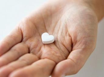 hand holding heart-shaped pill