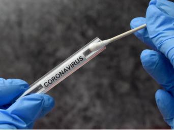 hands with PPE gloves on handling a coronavirus nasal sample, putting it into a sample tube. 