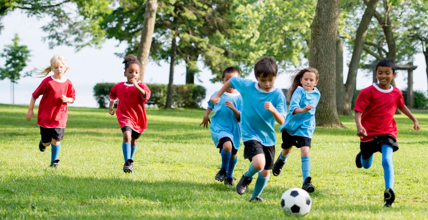 A group of kids playing soccer in a park