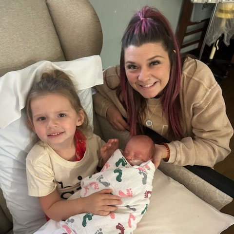 Kirsti Miller is crouching next to hear children in a hospital chair.