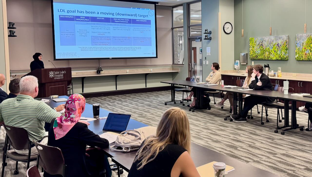 A group of researchers look at a presentation on a screen in a corporate conference room.