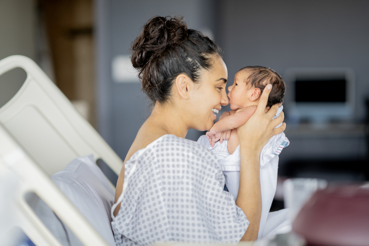 Mother Cradles Newborn Baby With Joyful Smile