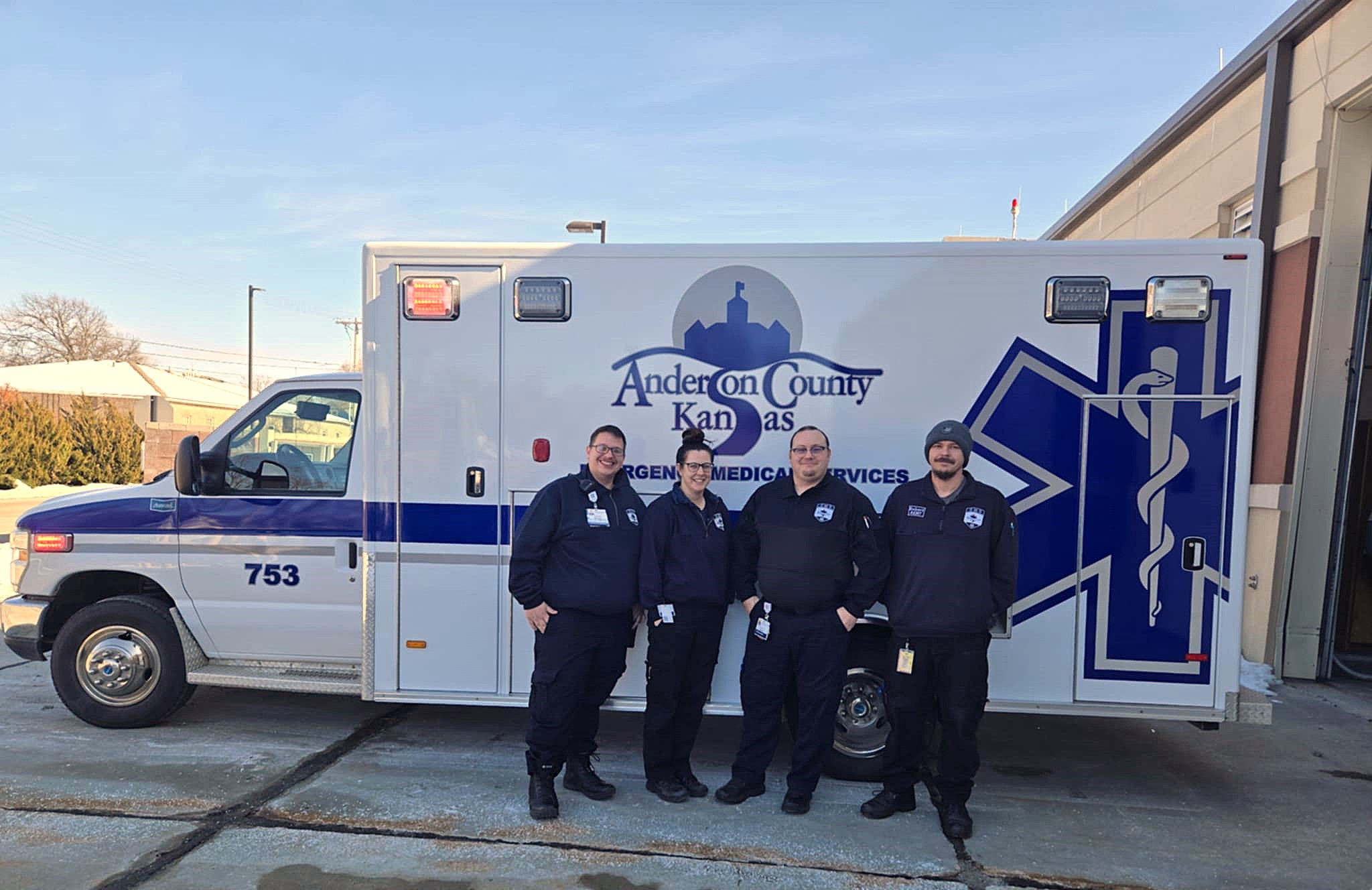 Four Anderson County EMS members pose near new ambulance