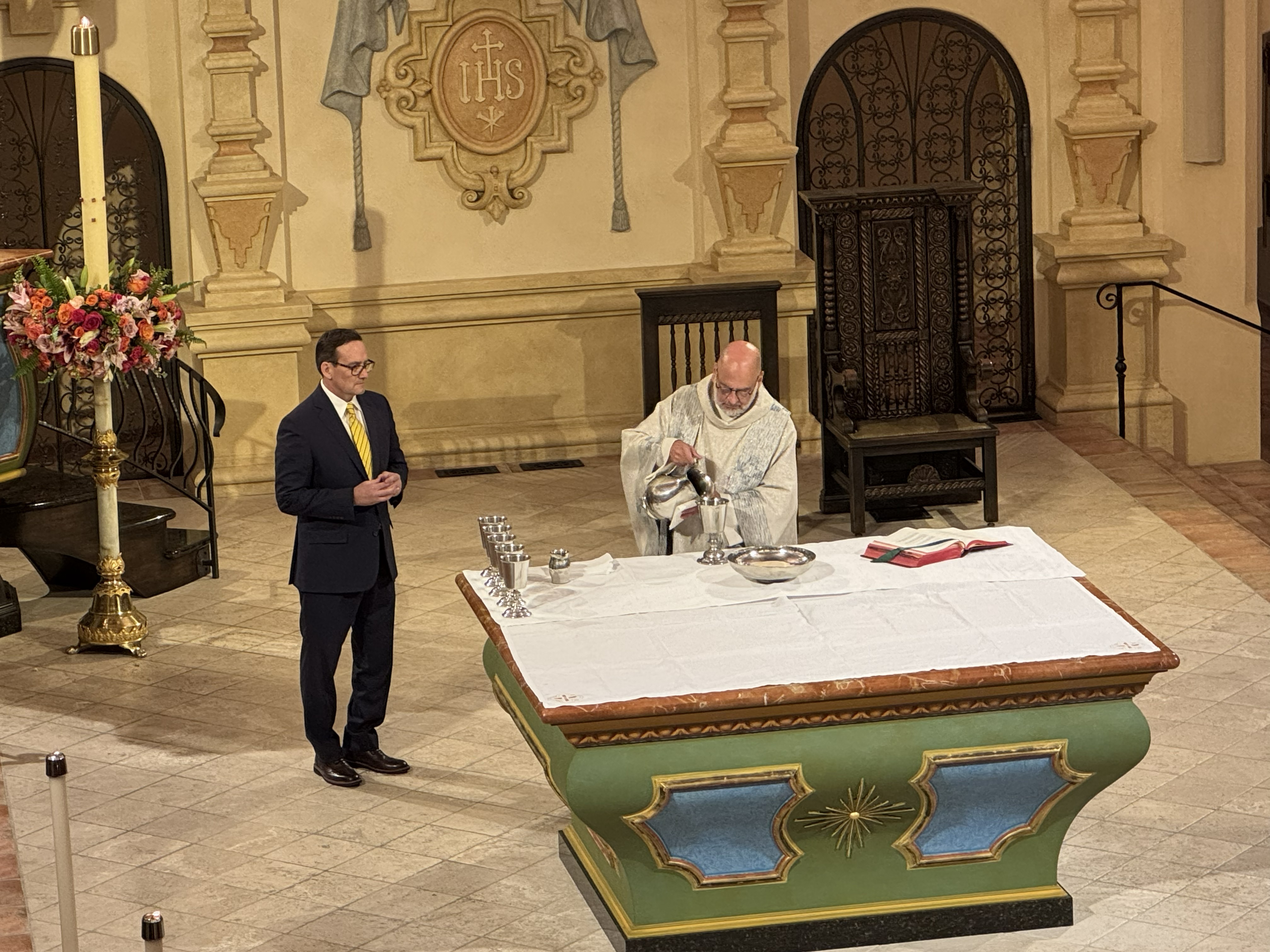 Father Greg pouring into a cup in the church 