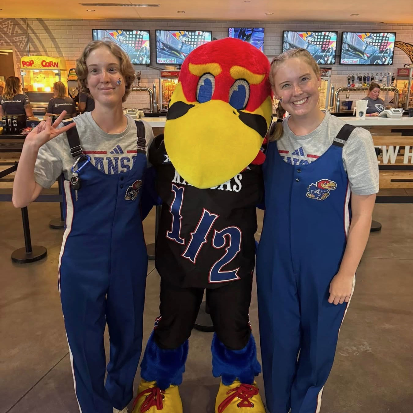 Annika and Peyton, NICU patients, are smiling at the camera wearing Kansas University attire with the Baby Jay mascot.