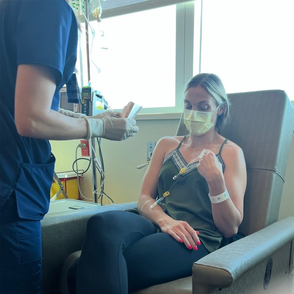 Cancer patient Kelsie is sitting in a clinic receiving IV medicines.