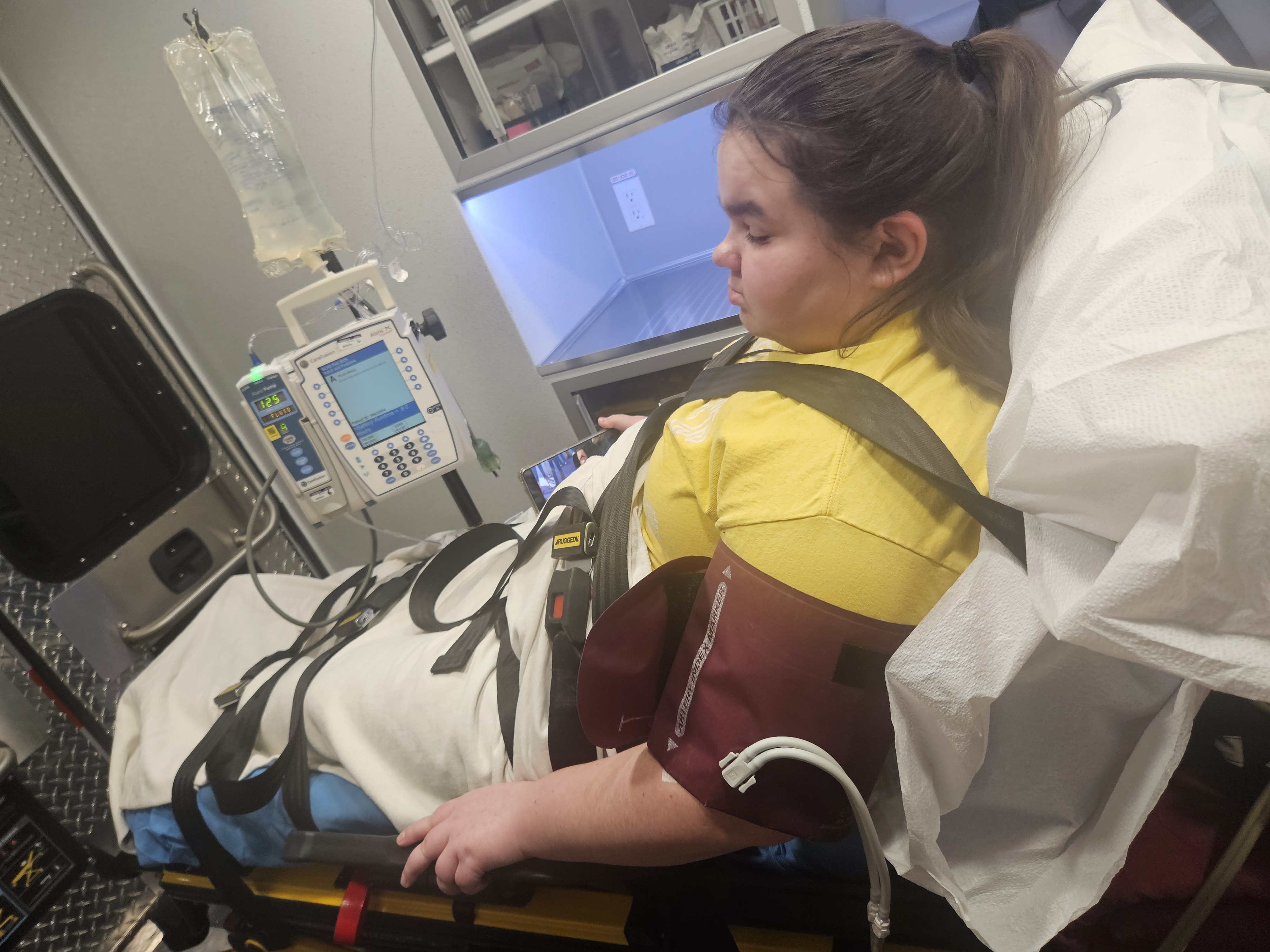 Kaylee laying inside an ambulance while laying on a gurney. 