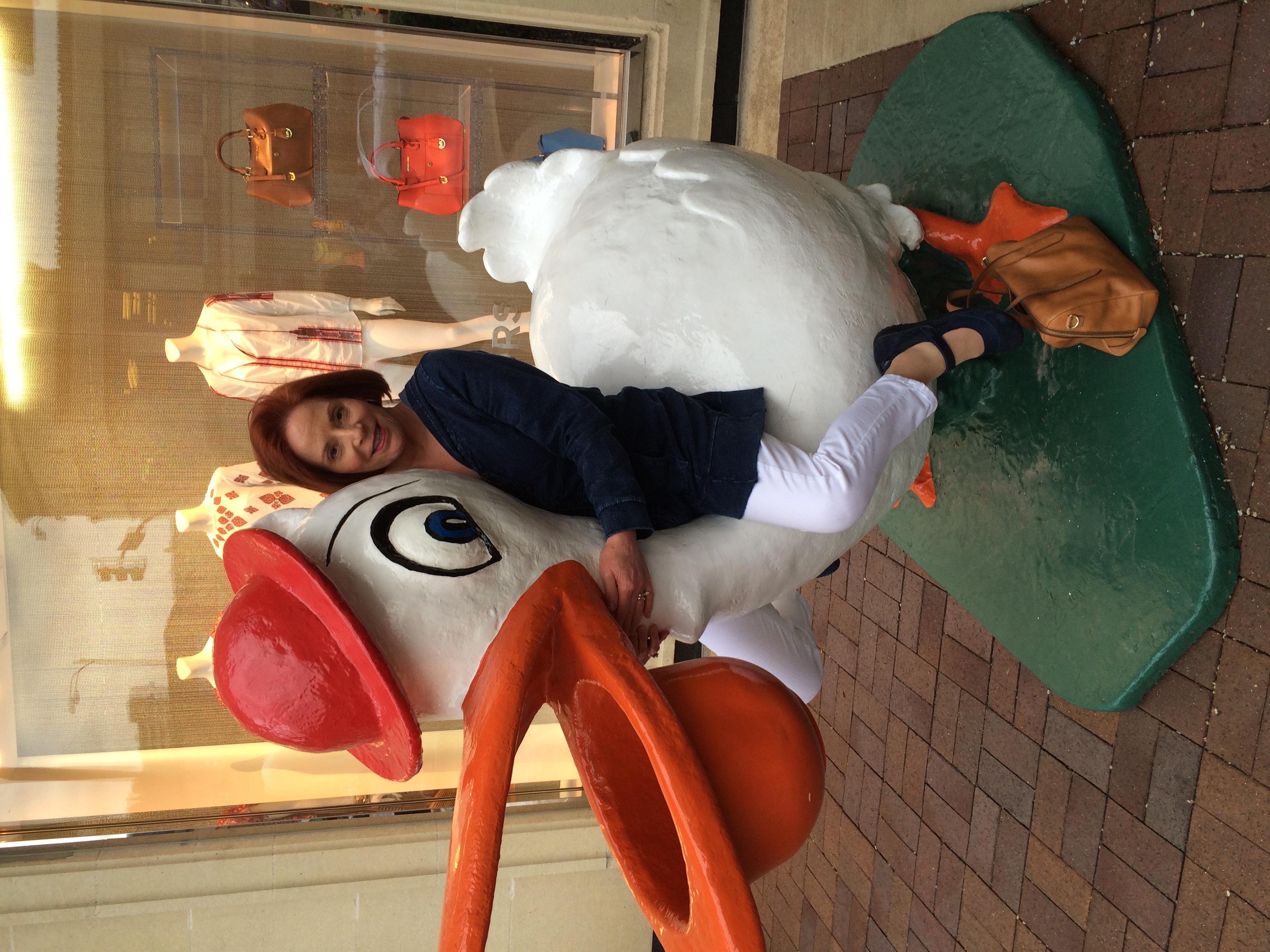 Gayle Seward sitting on a pelican statue in a mall store 