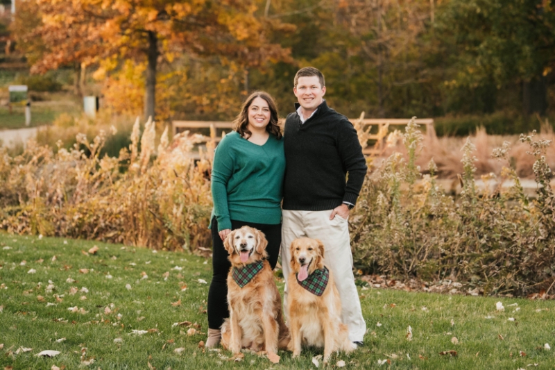 A woman smiling with her partner and two dogs.